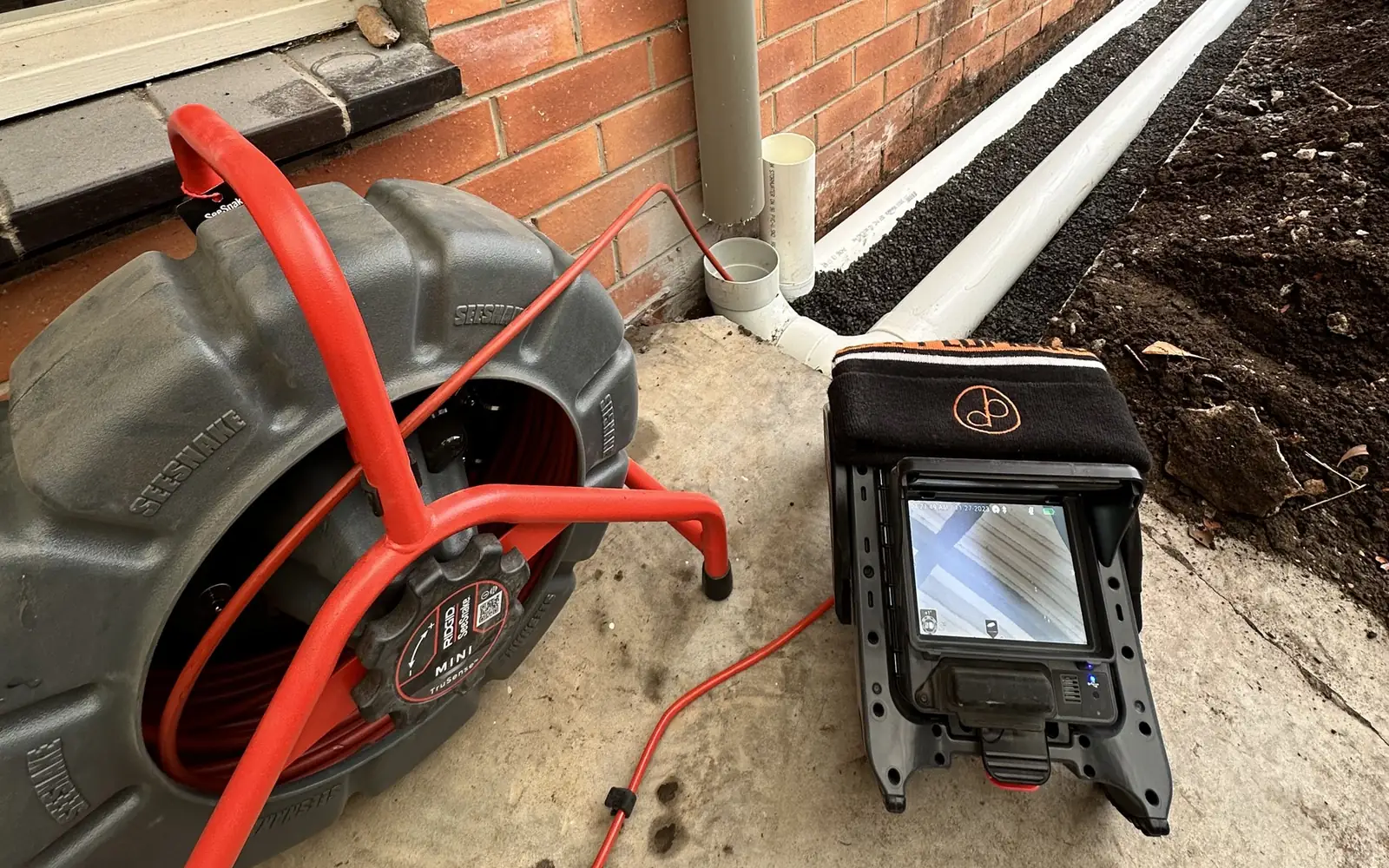CCTV drain inspection in Geelong: a Bay Plumbing drain camera reel and monitor set up beside a house on a job.