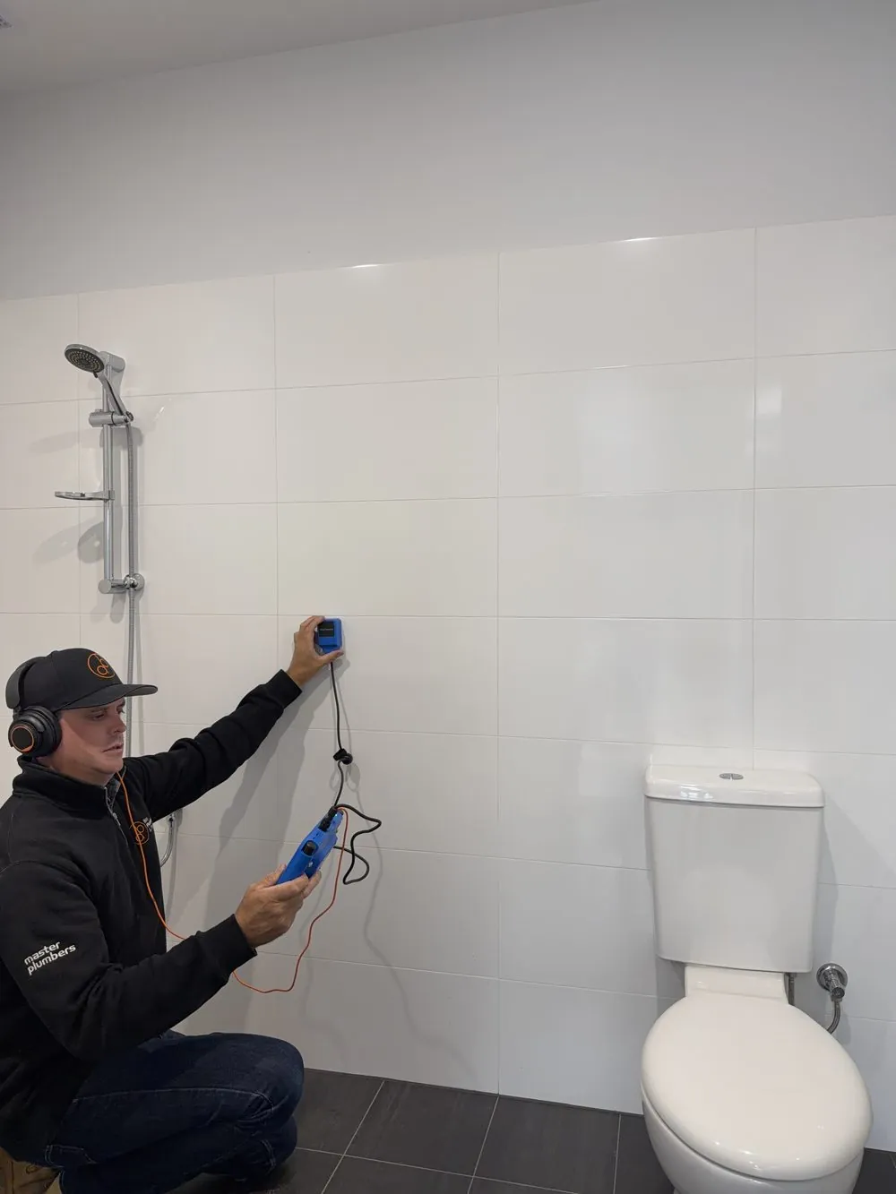 Bay Plumbing technician scanning a tiled wall with leak detection equipment in Geelong
